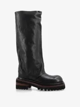 Bota de caña alta confeccionada en cuero premium color negro, con silueta relajada y diseño de caña ancha. Presenta una suela track dentada con detalles en contraste y punta redondeada.