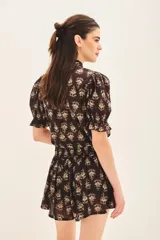 Short de voile de algodón con estampado floral en tonos beige sobre fondo negro. Presenta un diseño de corte amplio con cintura elástica y lazo ajustable para un calce cómodo.