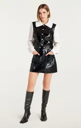 Campera negra de cuero sintético con mangas largas de punto acanalado color crema.