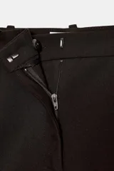 Falda pantalón corta de tiro medio color beige claro, con cierre frontal y detalle de cinturón negro con hebilla metálica redonda dorada.