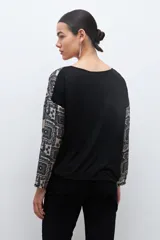 Blusa beige con estampado de arabescos en azul, con escote en V y mangas largas.