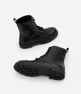 Bota estilo coturno de caña media, confeccionada en poliuretano con acabado liso. Presenta cierre mediante cordones frontales con ojalillos metálicos y suela track robusta.