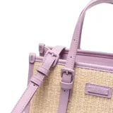Cartera mediana tipo tote de diseño estructurado, confeccionada en material símil rafia con detalles en cuero sintético color lila. Cuenta con doble asa de mano, correas decorativas frontales con hebillas, etiqueta con el logo de la marca y correa ajustable para el hombro.