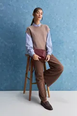 Chaleco de tejido de punto color beige claro, con cuello redondo y diseño de líneas limpias con hombros caídos y terminaciones acanaladas.