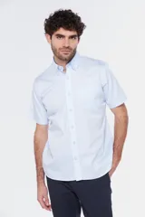 Camisa de manga corta color celeste claro, con cuello abotonado (button-down) y un bolsillo de parche en el pecho.