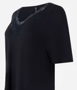 Pijama de dos piezas color negro confeccionado en viscolycra, compuesto por una remera de manga corta con cuello en V y detalles de encaje, y un pantalón capri con cintura elástica.