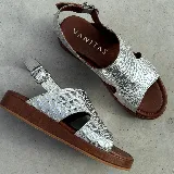 Sandalias de cuero color blanco con textura tipo reptil, plataforma marrón y hebilla metálica plateada.