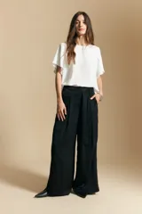 Top de color azul, con escote redondo a la base y mangas cortas amplias con caída fluida. Presenta una silueta relajada y un diseño minimalista.