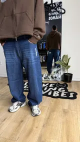 Pantalón de jean azul oscuro de corte wide leg, con diseño holgado y tiro medio. Presenta un pequeño bordado con alas en el bolsillo delantero.