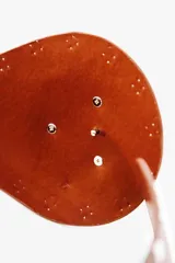 Cinturón ancho de cuero color marrón, con apliques de tachas plateadas y hebilla circular plateada.