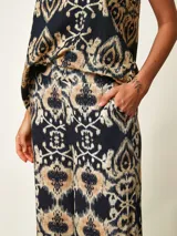 Pantalon tipo palazzo color negro con estampado paisley en tonos beige y blanco, corte holgado y tiro medio.
