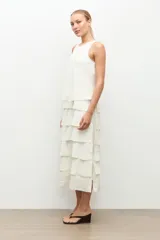 Maxi vestido crudo sin mangas con múltiples volados horizontales escalonados y escote redondo.