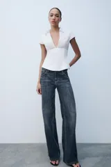 Top de popelina blanca de corte corsetero, con escote en pico pronunciado, cuello tipo solapa, mangas muy cortas y costuras marcadas.
