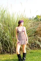 Vestido corto negro con estampado de plumas doradas, escote en V, breteles finos cruzados en la espalda, cut-outs laterales y volado en el ruedo.