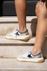 Championes urbanos de cuero con diseño de estrella lateral en color negro, detalles metalizados en el talón y puntera de gamuza. Cuenta con plataforma blanca y suela de goma color caramelo.