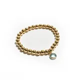 Pulsera elástica con cuentas doradas y dije colgante circular con piedra celeste.