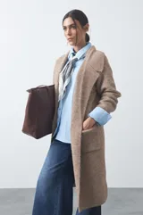Cardigan de tejido de punto gris, con silueta larga, frente abierto, solapas clásicas y bolsillos aplicados en los laterales.