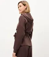 Campera deportiva Get Over de color negro, confeccionada en mezcla de poliéster, modal y elastano. Presenta diseño utilitario con capucha, cierre frontal de botones, bolsillos con solapa en el pecho, mangas largas y lazo ajustable en la cintura.