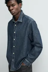 Camisa de corte relajado confeccionada en denim de algodón, con cuello solapa, manga larga con puños abotonados y cierre frontal de botones.
