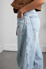 Jean de corte recto y tiro alto con diseño bicolor, presentando un panel lateral en un tono de azul ligeramente más oscuro que el resto de la prenda. Confeccionado en denim de lavado claro.