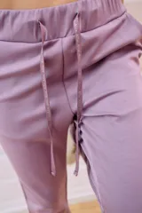 Pantalón babucha deportivo color lila, con elástico en la cintura y puños, cordones regulables y dos bolsillos laterales.