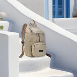 Mochila de diseño acolchado en color beige, con compartimento principal superior y bolsillo frontal con cierre. Cuenta con correas ajustables y tiradores de cierre en tono a juego.