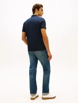 Chomba azul marino Tommy Hilfiger de manga corta y corte regular, confeccionada en algodón. Cuenta con cuello polo, cierre de cremallera parcial con detalles tricolor en el interior y logo bordado en el pecho.