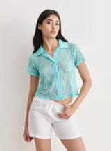 Camisa de manga corta color turquesa, confeccionada en tela de encaje con diseño floral. Presenta cuello camisero y cierre frontal con botones.