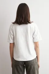 Remera blanca de manga corta raglán con detalle de vainillas, cuello redondo y corte clásico.