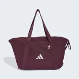 Bolso deportivo Adidas de color bordó, con asas superiores, correa ajustable cruzada y el logo de la marca impreso en blanco en la parte frontal. Cuenta con cierre superior y bolsillo frontal con cremallera.