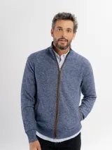 Campera tejida de punto jaspeado en tono azul, con cierre frontal completo, cuello alto y detalles de ribete en color marrón en los bolsillos y a lo largo del cierre. Presenta puños y ruedo acanalados.