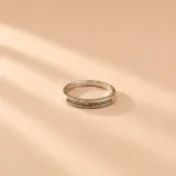 Anillo de oro blanco 18K con diseño medio sin fin, decorado con una línea de circonias engastadas en el frente.