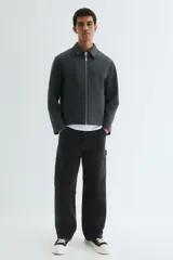 Sobrecamisa de fieltro color gris oscuro, con cuello, cierre bidireccional y bolsillos insertados en la parte delantera. Presenta un corte estándar y no tiene forro.