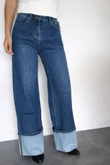 Pantalón de jean corte wide leg en color azul oscuro, con tiro medio-alto y detalle de dobladillo ancho en la botamanga que contrasta con el tono del resto de la prenda.