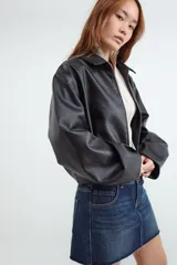 Campera bomber de manga larga confeccionada en tejido efecto cuero. Presenta un diseño con cuello clásico, cierre frontal con cremallera y bajo con detalle abullonado.