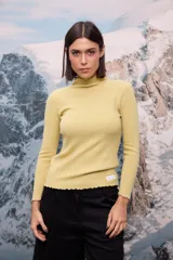 Polera de tejido de punto fino color amarillo, con cuello alto, mangas largas y terminaciones con detalle de ondas (ruloté) en cuello, puños y ruedo.