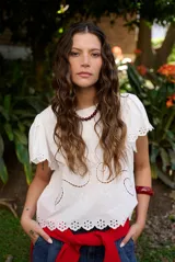 Blusa blanca de manga corta con detalles de bordados y perforaciones, cuello redondo y diseño holgado.
