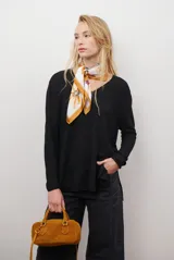 Sweater de tejido de punto color beige, con escote en V y mangas largas. Presenta un diseño básico y versátil de corte recto.