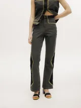 Pantalón de jean tiro alto con corte ochentoso y terminación oxford. Presenta paneles laterales en contraste y costuras decorativas en color amarillo a lo largo de las piernas.