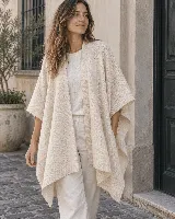 Ruana de lana color beige, con diseño abierto, caída envolvente y terminaciones acanaladas en los bordes.