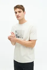 Remera de manga corta color beige con estampado fotográfico en el pecho. Presenta un corte regular y cuello redondo.