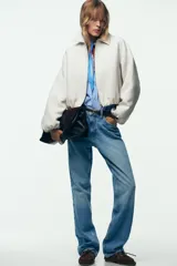 Chaqueta bomber negra con cuello solapa, manga larga abullonada y puños elásticos. Presenta falsos bolsillos de doble vivo en la parte delantera y cierre frontal con cremallera.