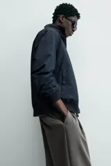 Cazadora azul marino de corte regular fit, confeccionada en tejido técnico repelente al agua. Presenta cuello subido, manga larga, bolsillos de vivo en cadera, bolsillo interior y acabados en rib en puños y bajo. Cierre frontal de cremallera oculta por solapa con botones a presión.