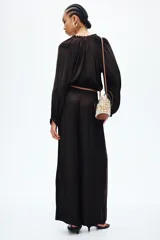 Pantalón marrón oscuro de corte holgado y piernas amplias, con cintura elástica fruncida y cordón ajustable.