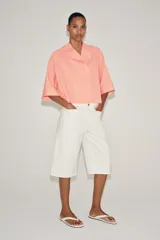 Camisa ZARA Woman Collection confeccionada en hilatura con viscosa, con diseño de rayas finas y color salmón. Presenta cuello perkins, mangas por debajo del codo, bajo asimétrico y cierre frontal cruzado con botones.