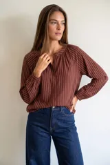 Blusa de corte oversize con estampado de rayas verticales, cuello redondo con pequeña abertura frontal abotonada y mangas largas con puños elásticos.
