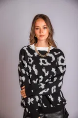 Buzo de punto color negro con estampado animal print en gris claro, de corte holgado y manga larga.