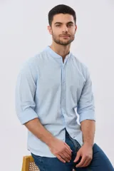 Camisa de lino y algodón color beige, de manga larga, con cuello mao y cierre frontal con botones. Presenta un pequeño bordado al tono en el pecho.