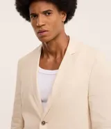 Saco de traje masculino confeccionado en mezcla de lino y viscosa, con cierre frontal de dos botones, bolsillos laterales con solapa y medio forro interior.