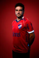 Camiseta de fútbol Umbro del Club Nacional de Football, modelo Away 1. Diseño principal en color rojo con cuello en V azul, detalles blancos en los hombros y puños blancos. Incluye el escudo del club, logo de Umbro y sponsors estampados.